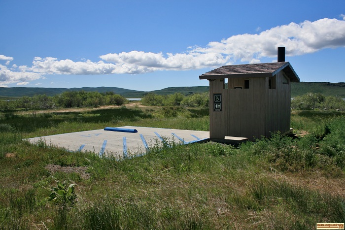 This outhouse is handicap accessible complete with a cement parking spot marked "Handicapped".