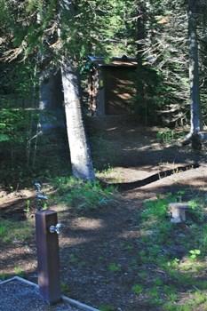 Pettit Campground drinking water with outhouse in background.